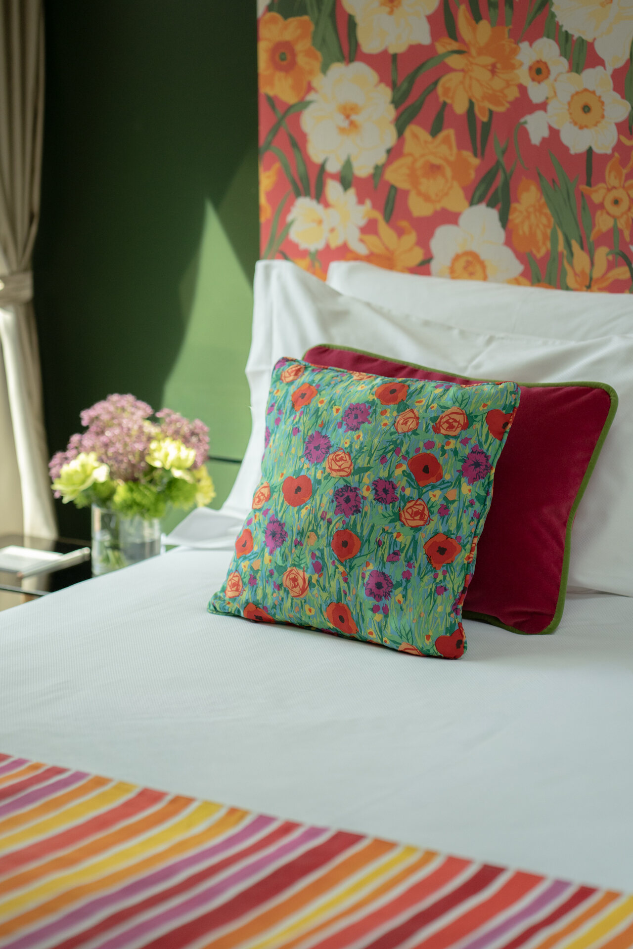 A suite at Speronari Suites — green walls, floral headboard and striped textiles in morning light